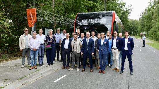 Betrokken partijen en genodigden poseren voor een lijnbus, klik voor een vergroting