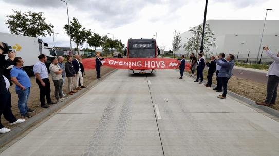Een bus rijdt door een feestelijk lint met daarop de tekst 'Opening HOV3', klik voor een vergroting