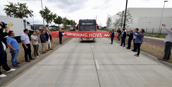 Een bus rijdt door een feestelijk lint met daarop de tekst 'Opening HOV3'