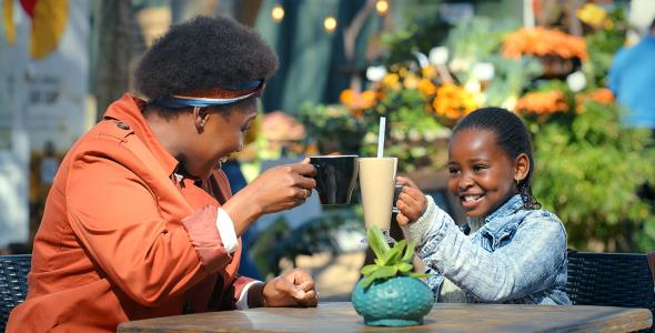 Een moeder drinkt op het terras een drankje met haar dochter.