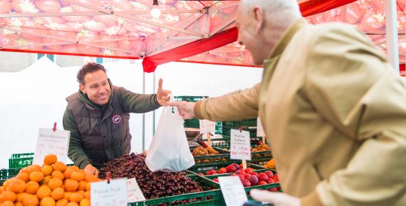 Op deze foto staan twee personen op de weekmarkt.