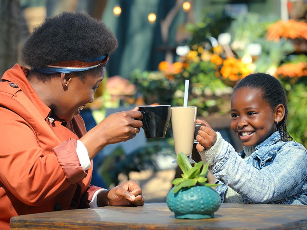 Een moeder drinkt op het terras een drankje met haar dochter.