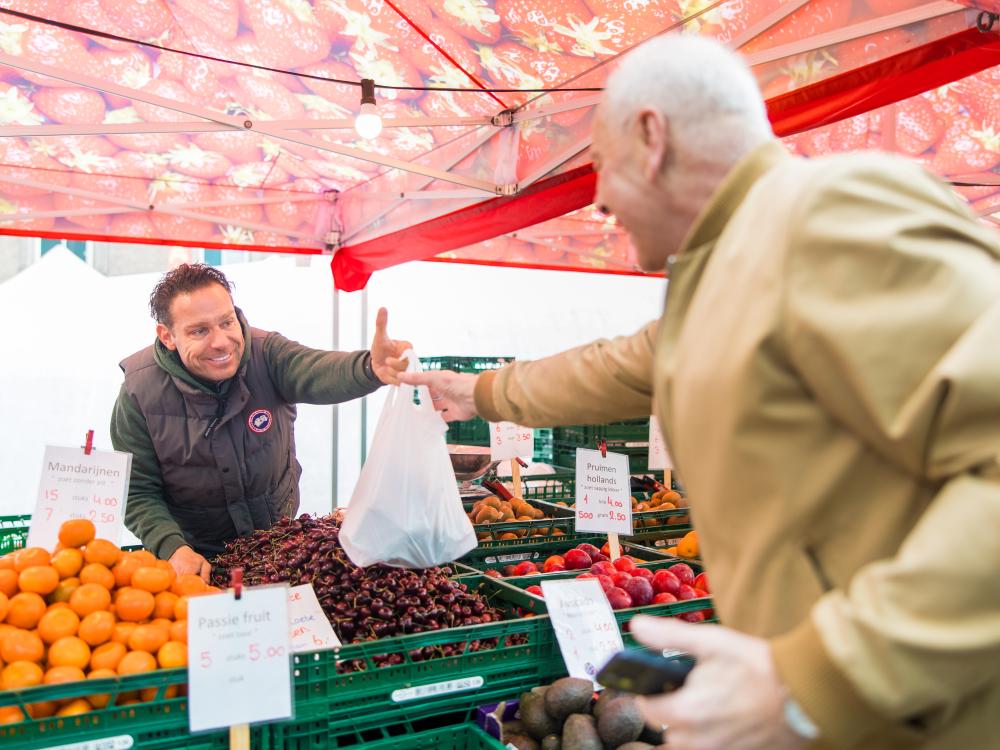 Op deze foto staan twee personen op de weekmarkt.
